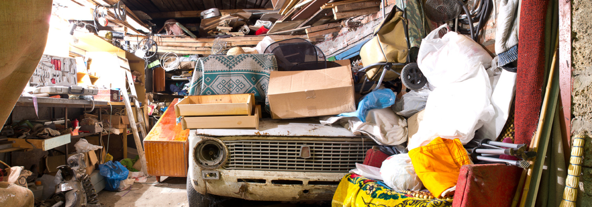 Roll Off Dumpster- Junk Removal- Garage inside. Old broken car, shelves with tools and stacks of things.