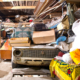 Roll Off Dumpster- Junk Removal- Garage inside. Old broken car, shelves with tools and stacks of things.